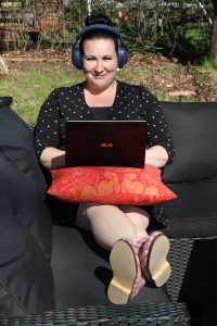 Jenny Nyman kannettavan tietokoneen kanssa puutarhassa