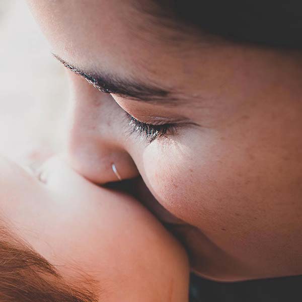 tuettu-loma Tuetut lomat aikuisten adoptoitujen ja adoptiovanhempien perheille, joissa on alaikäisiä lapsia. Lähikuvassa äiti suukottaa lapsen poskea.